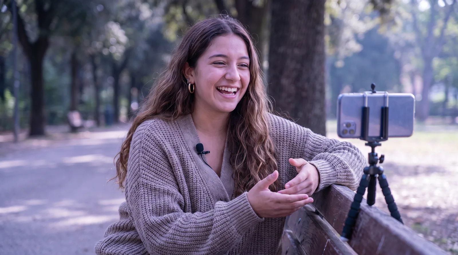 Woman recording a video in a park with a smartphone and lavalier microphone